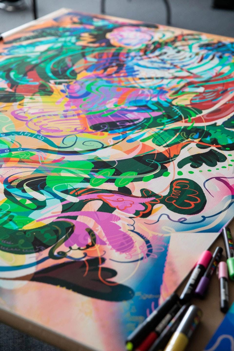 A close-up of one of Moses Sun's colorful abstract painting as it rests on a worktable.