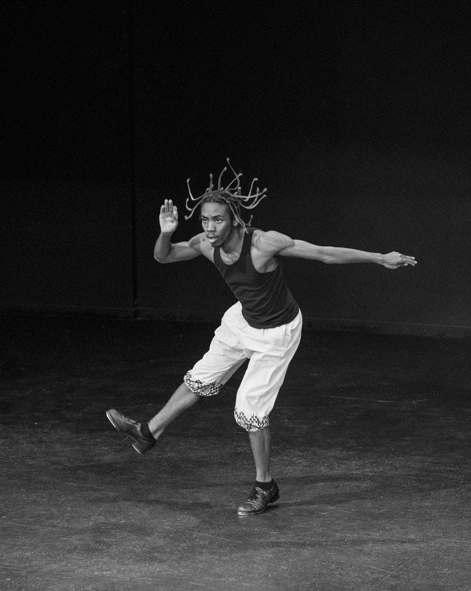 A black and white photo of Cipher Goings in mid-motion while tap dancing