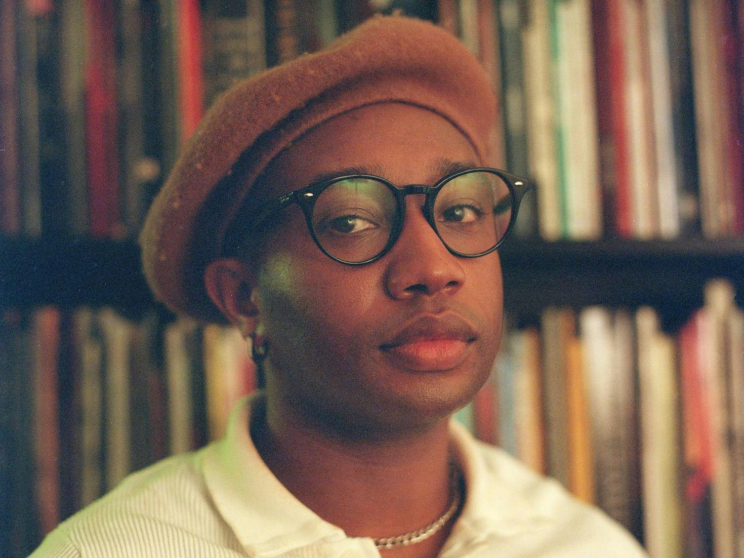 A person in a caramel-colored beret and black glasses