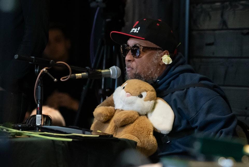 Riz Rollins speaks on the mic while holding a plush rabbit