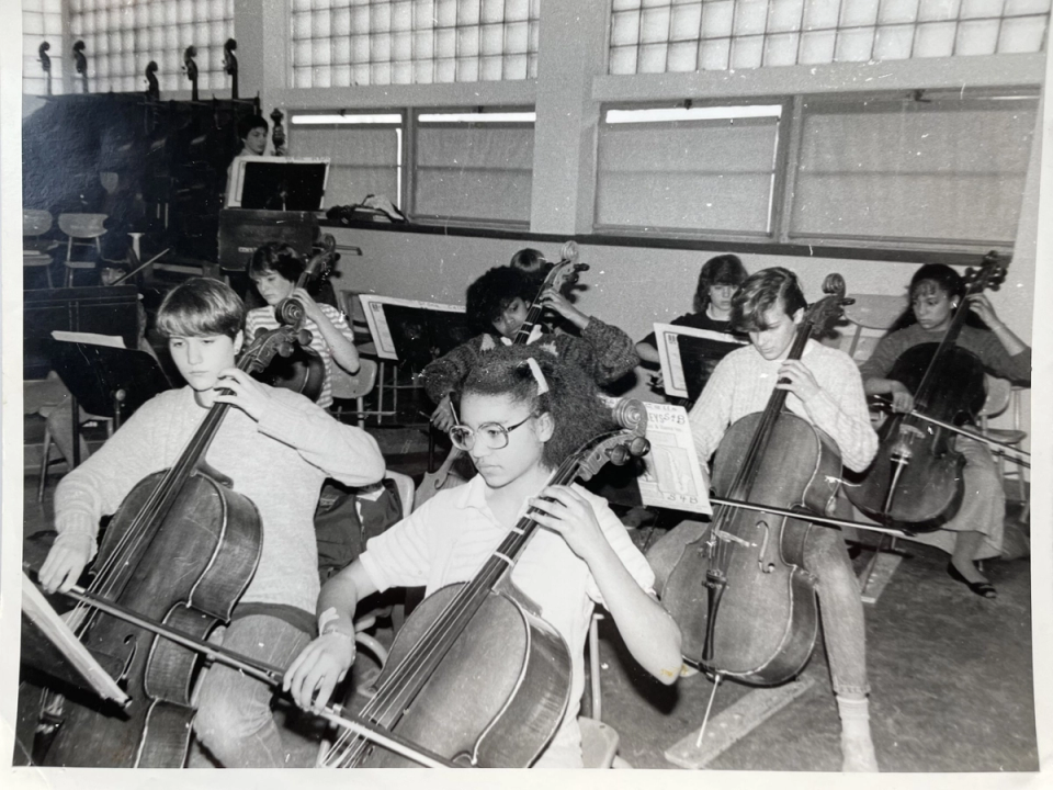 A black and white photo of Gretchen Yanover playing cello with her middle-school classmates