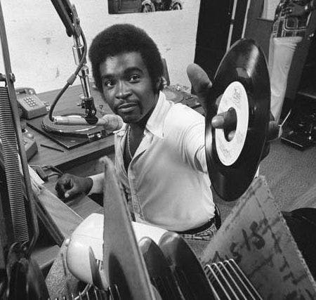 A man in a radio booth holding a record