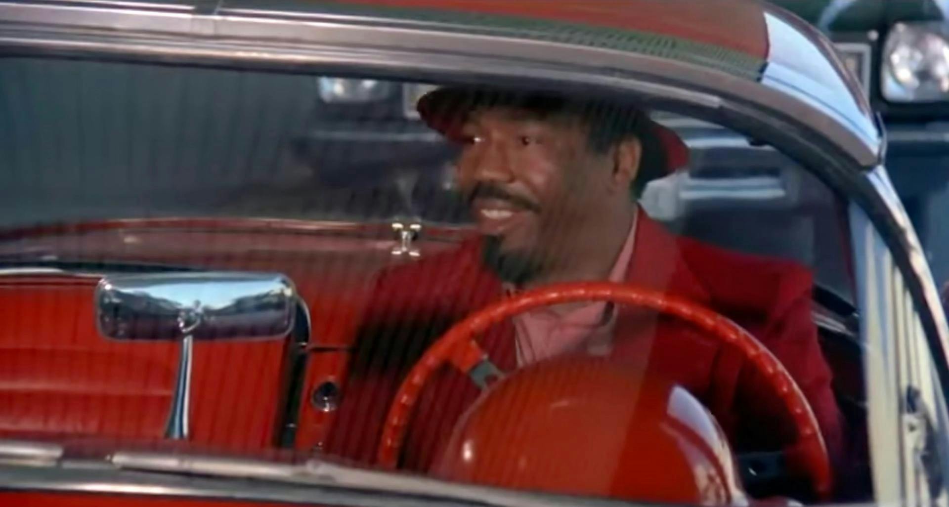 A man in a red suit and hat in a red car