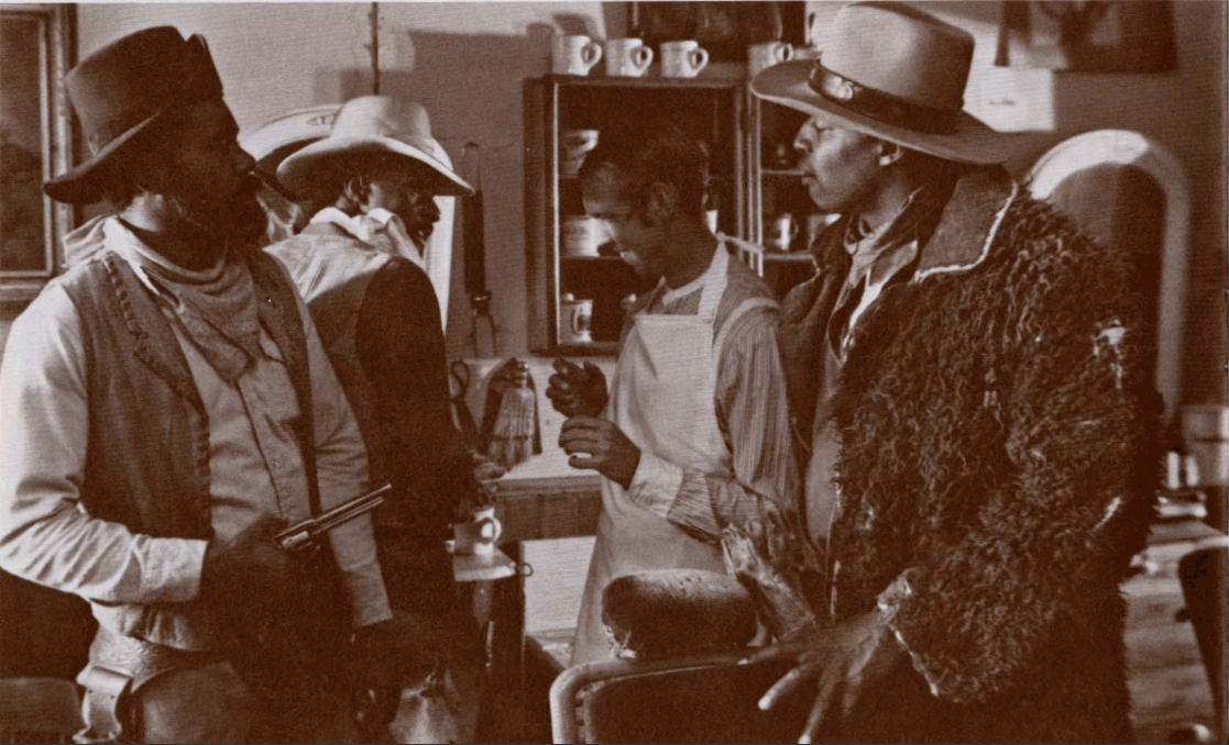 A sepia still of Black cowboys talking