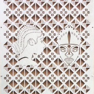 detail of metal-cut artwork featuring heads and a cowrie pattern