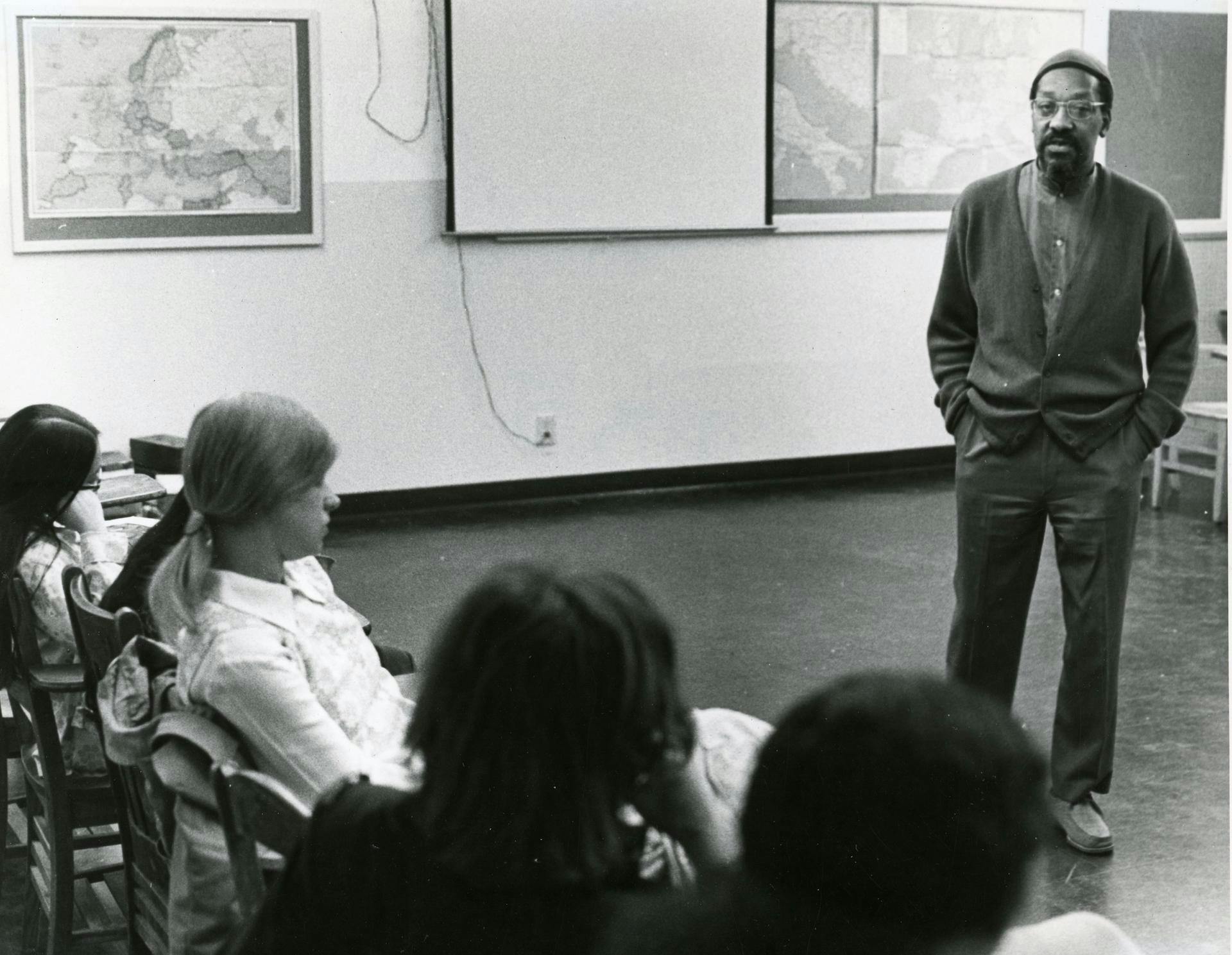 A black and white photo of a man teaching a class