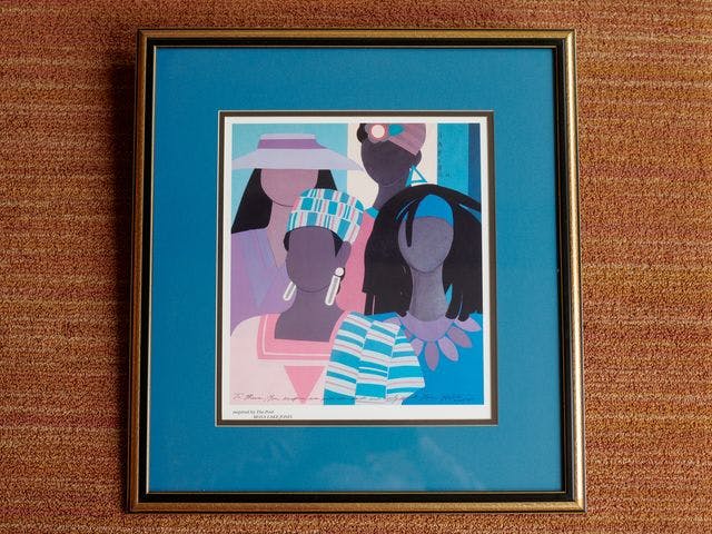photo of a framed poster with blues and purples, featuring four faceless people