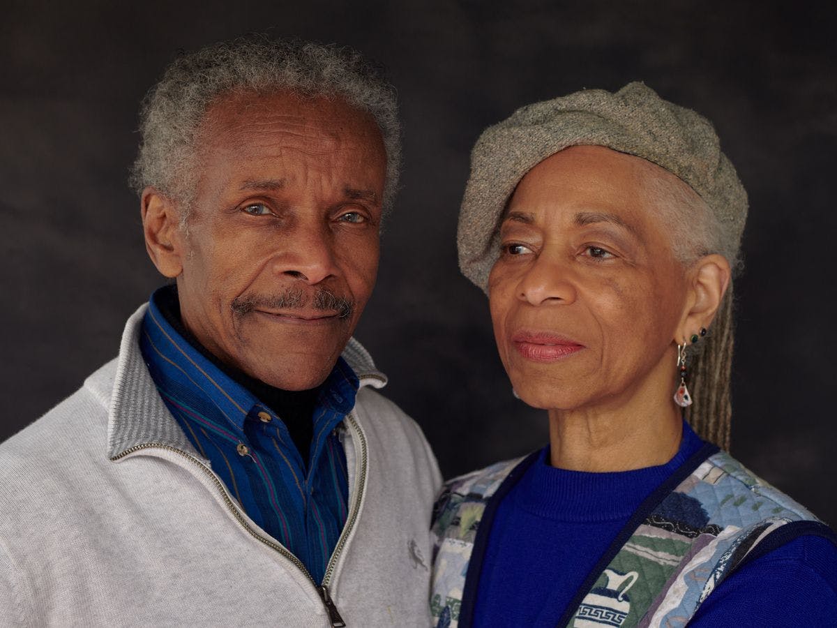 a close up portrait of two people, both wearing blue tones