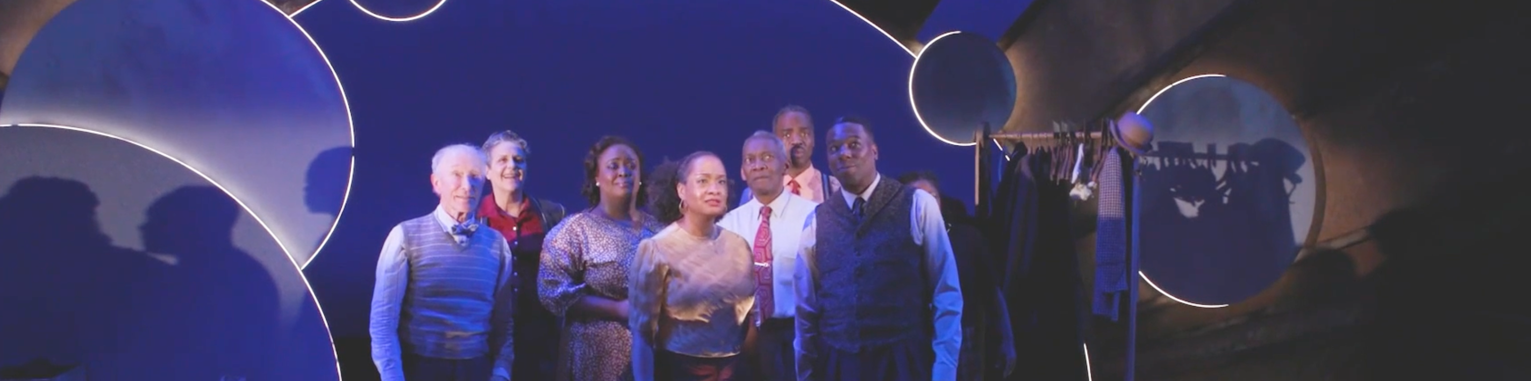 People standing on a stage with circles and looking into the distance