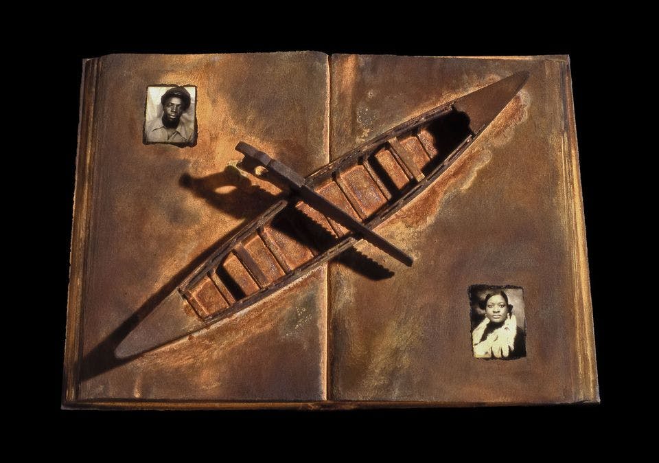 An open book painted in brown tones with a wooden boat placed diagonally across the spine