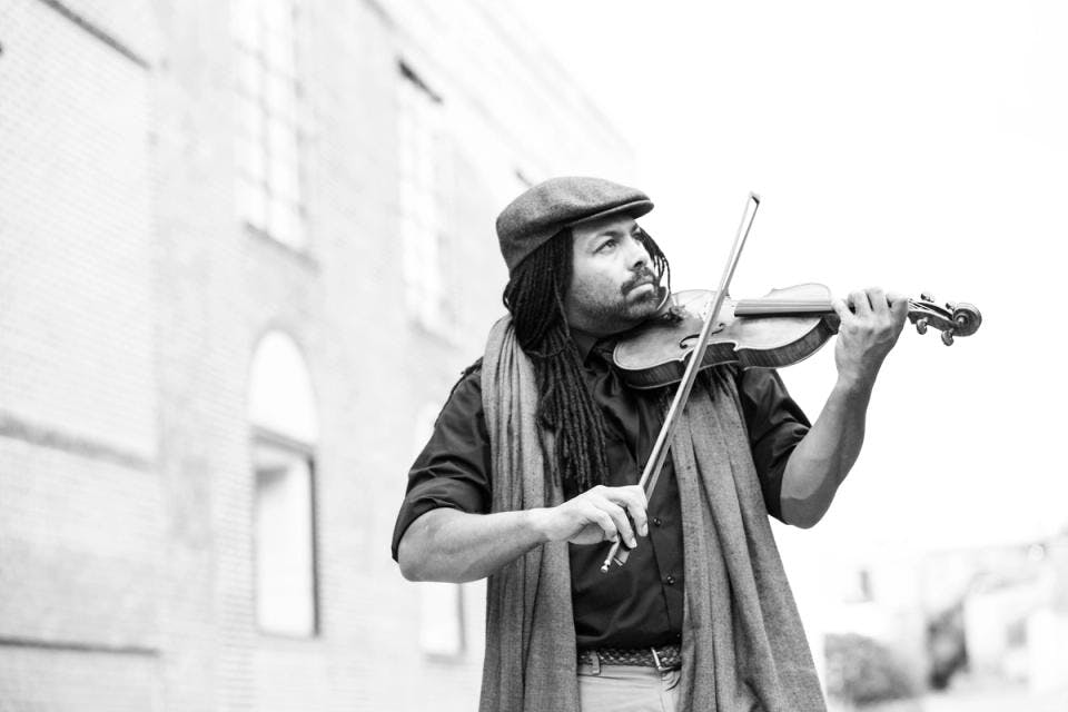 A black and white photo of a man playing the violin while looking into the distance