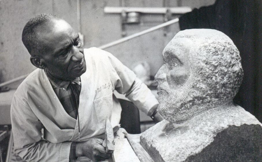 black and white photo of artist with a bust