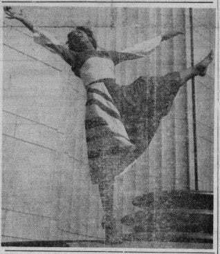 A black and white faded photo of a woman in a dance pose where one leg is up and her arms are raised