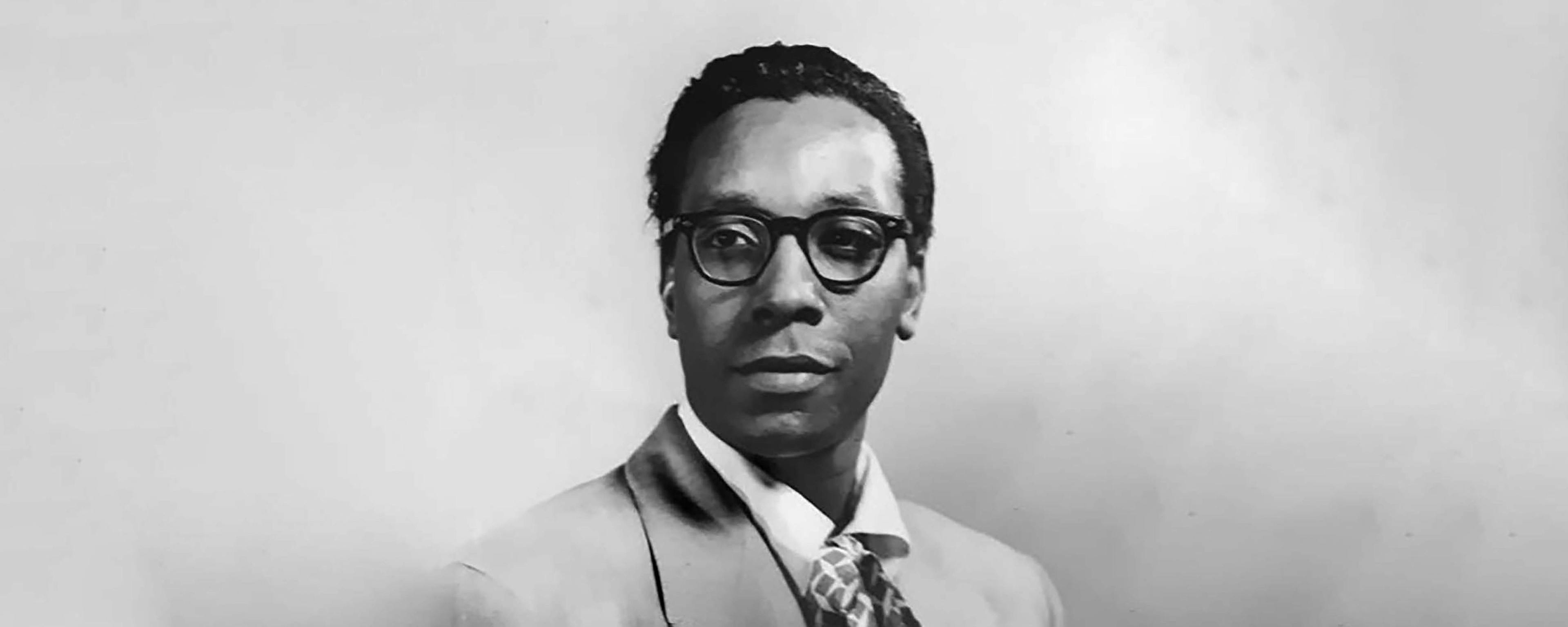 A black and white photo portrait of a man with glasses smiling