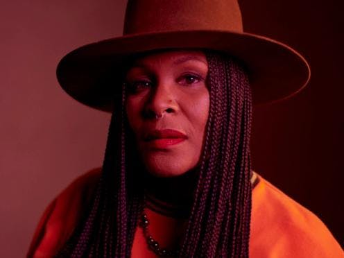 A portrait of a woman wearing an orange hat, staring pensively
