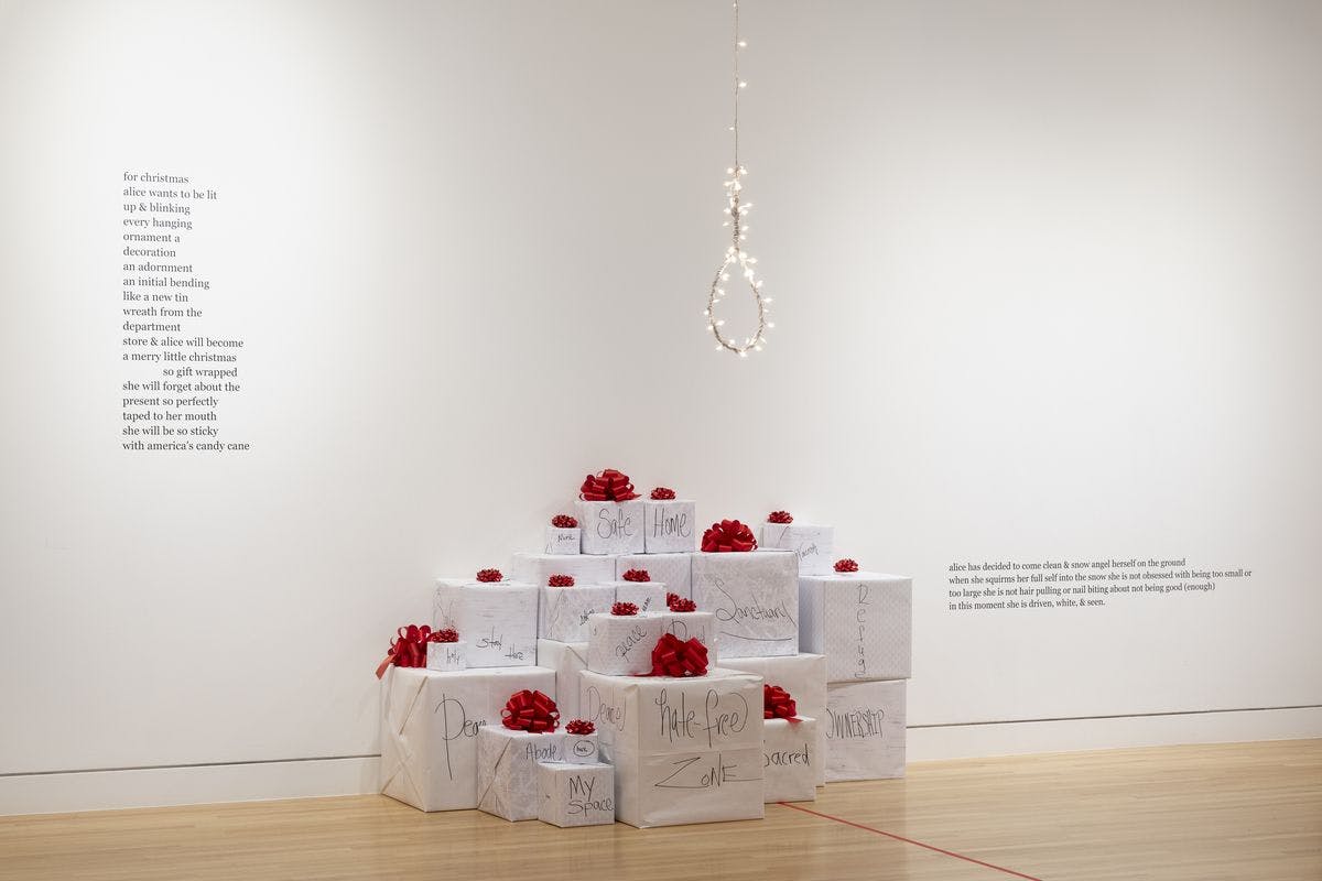 white boxes with red frills on top, a noose with string lights hangs above. A poem is written on the wall