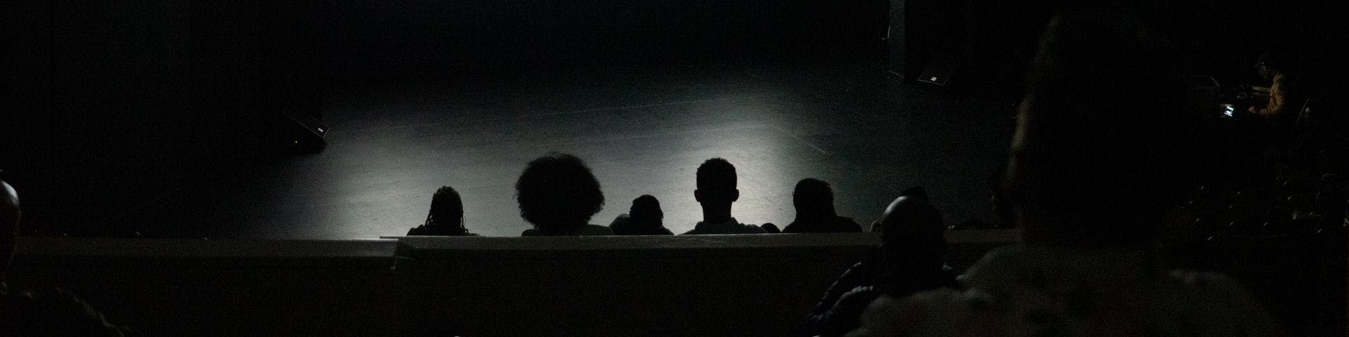 dim room with people watching a stage